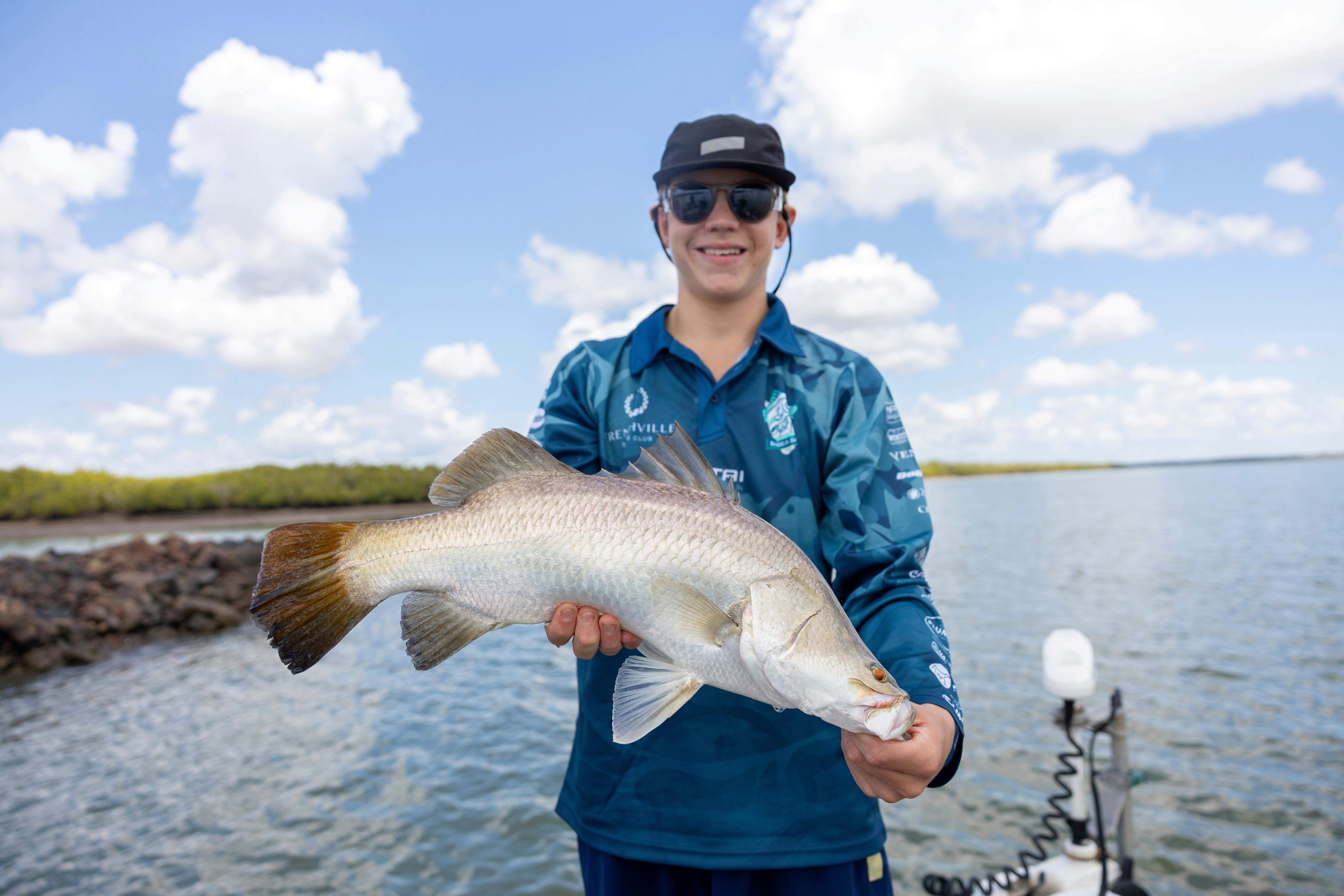 One angler holding a barramundi on a boat on the Fitzroy River.