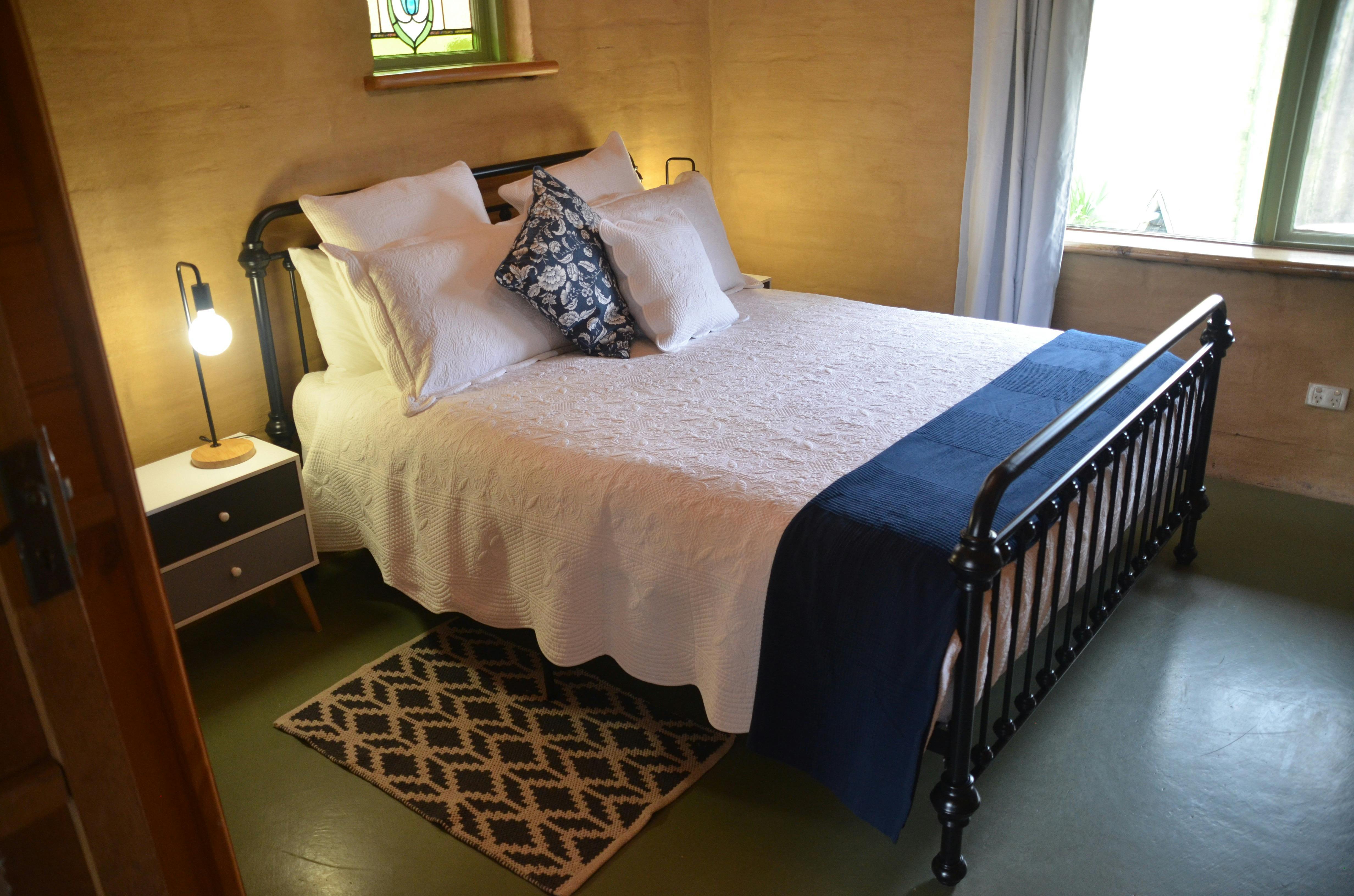 A queen-sized bed pictured within a rustic-looking cottage room
