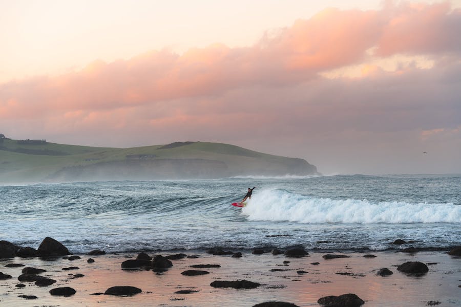 A surfer rides a wave at sunset