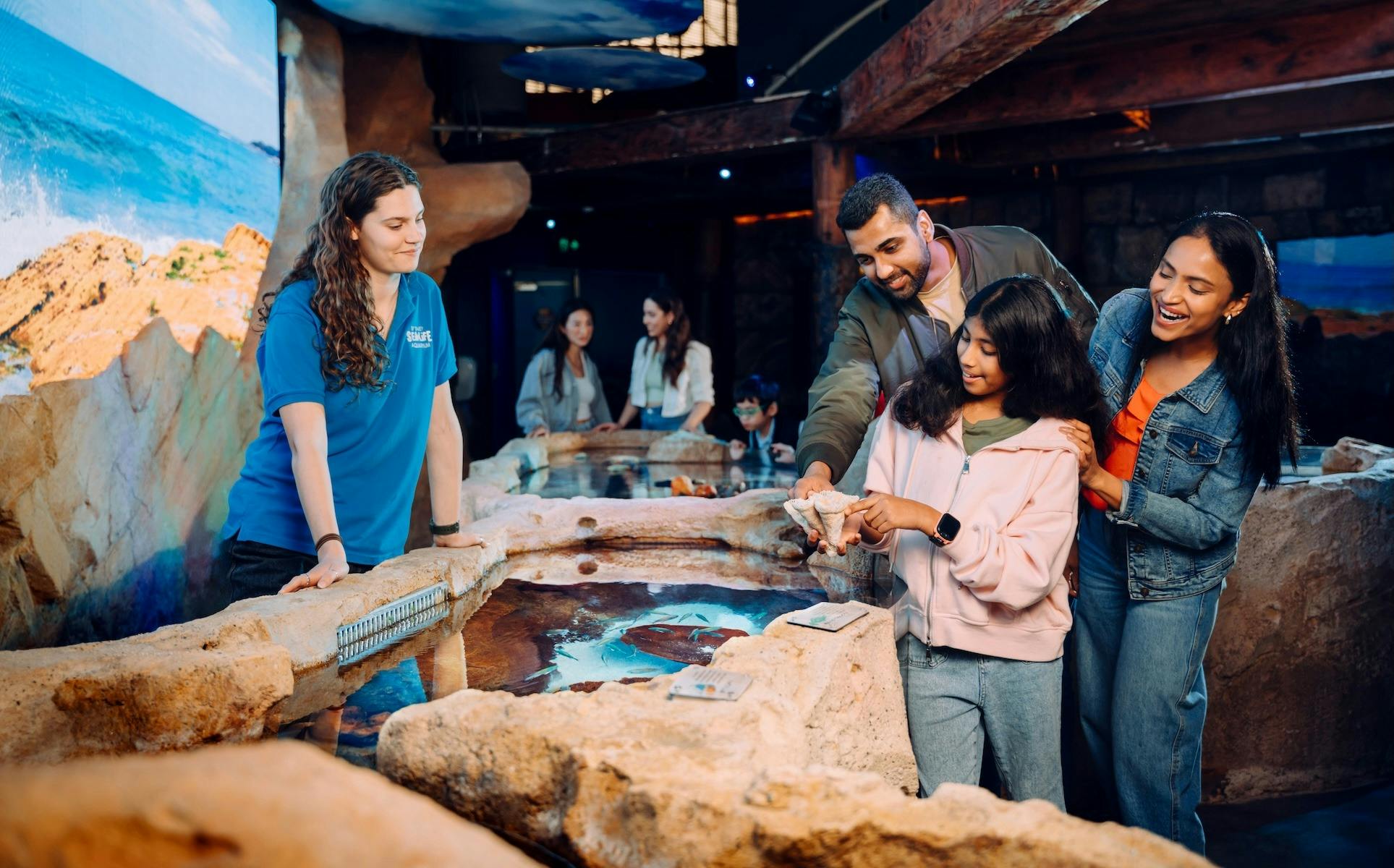 A family exploring the rockpool exhibit, guided by an aquarist at SEA LIFE Sydney
