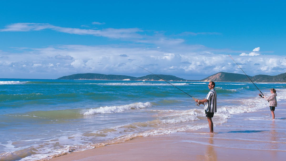 Couple fishing from beach, Rainbow Beach