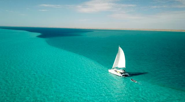 The sailing catamaran Shore Thing sailing in turquoise waters