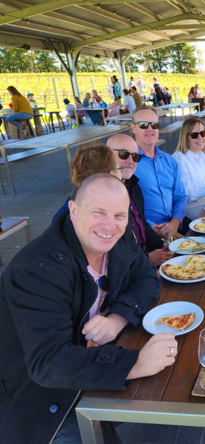 A group of people sitting at a table enjoying a meal together, with a variety of food and glasses of