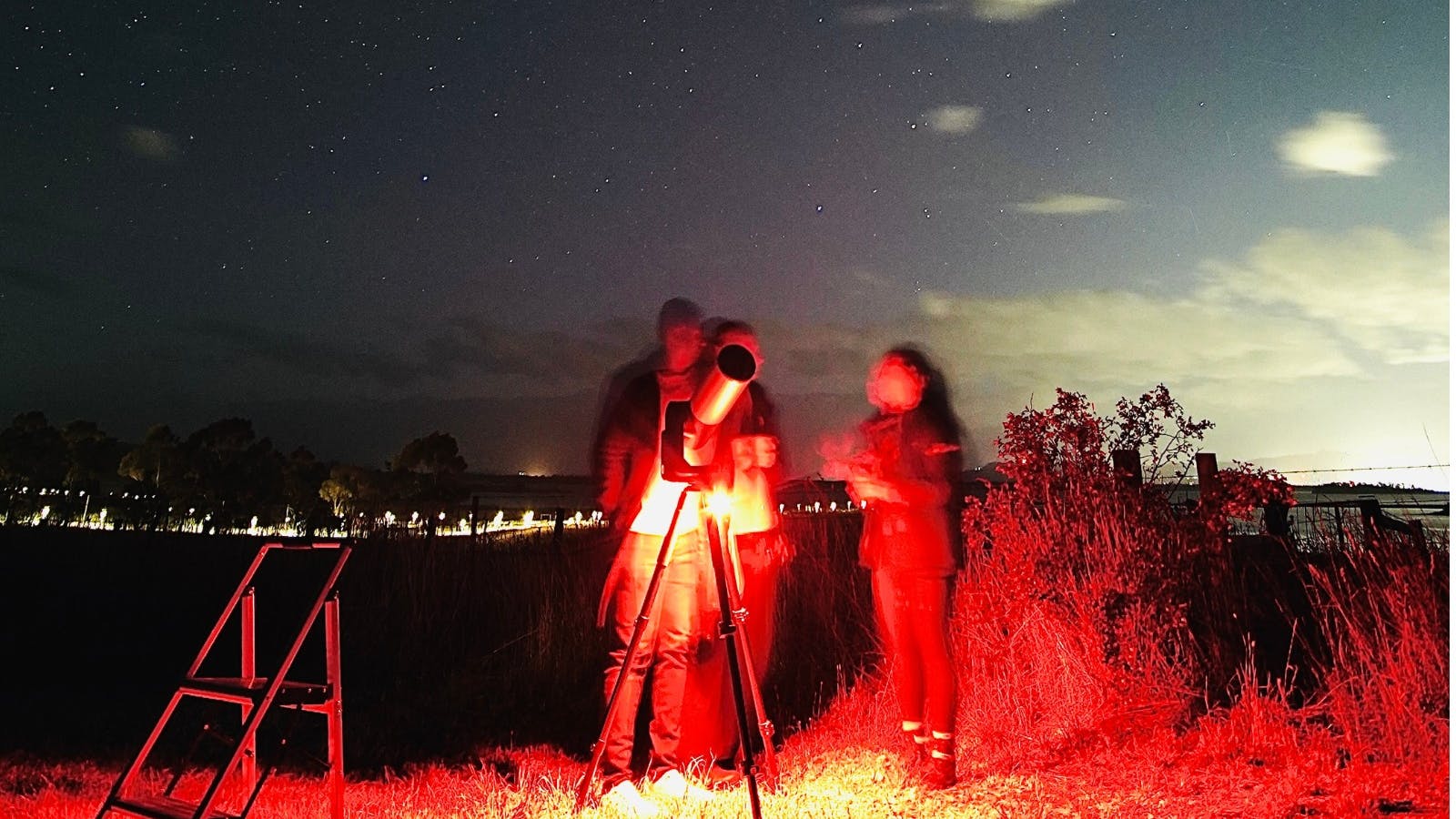 Guided stargazing with guests using red light to protect night vision.