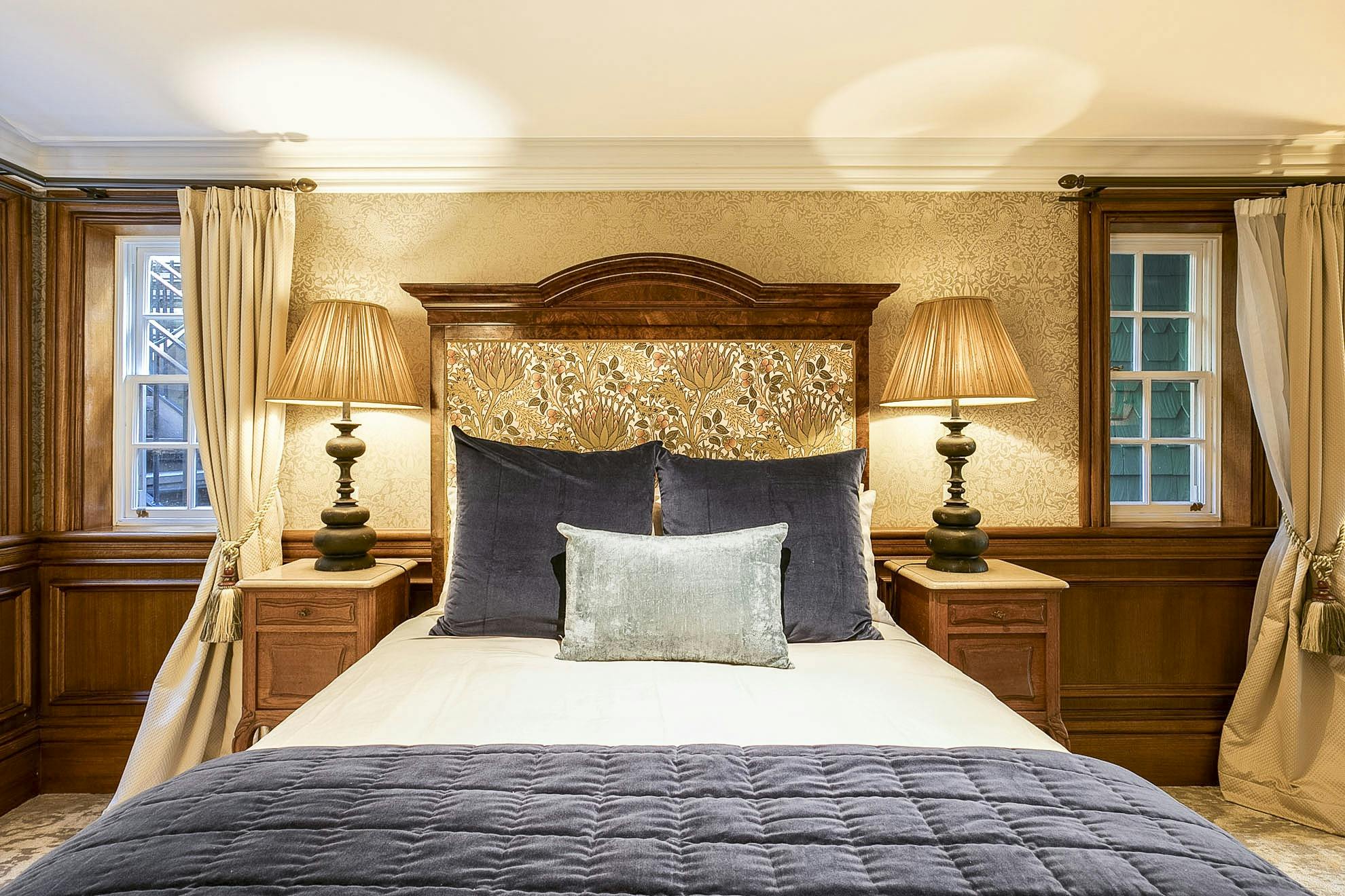 Features a luxurious queen bed set beneath an antique walnut frame and velvet drapes