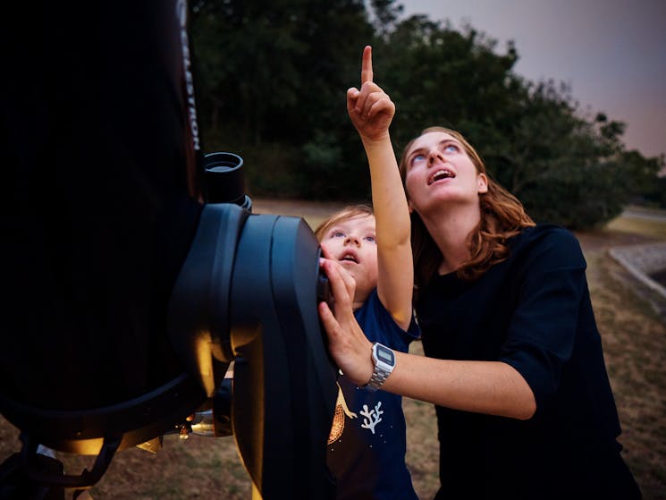 Child and adult by the telescope looking at the stars