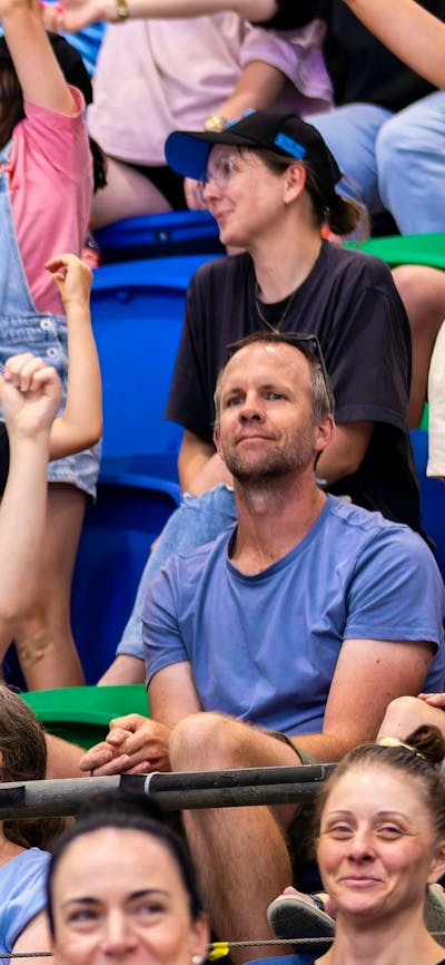 Two young fans cheering in the stands while waving a UC Capitals poster.