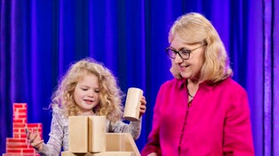 Female child playing with building blocks next to her grandmother