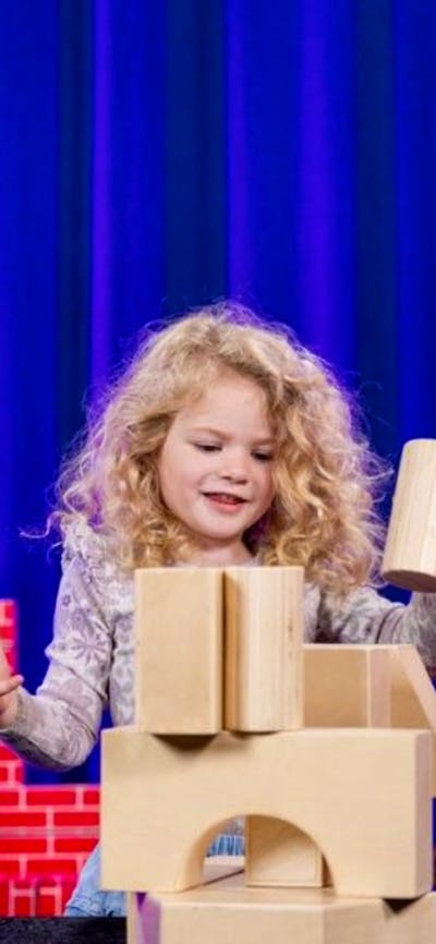 Female child playing with building blocks next to her grandmother