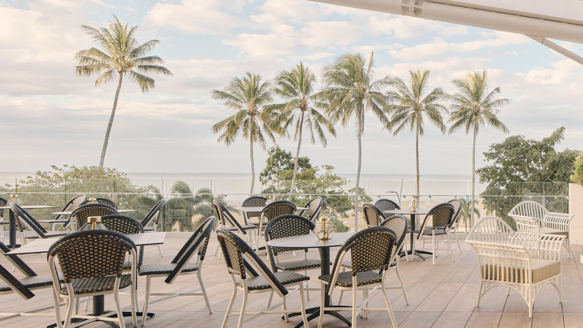 Tables on the balcony with palm trees in the background