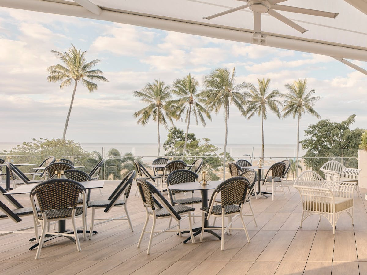 Tables on the balcony with palm trees in the background