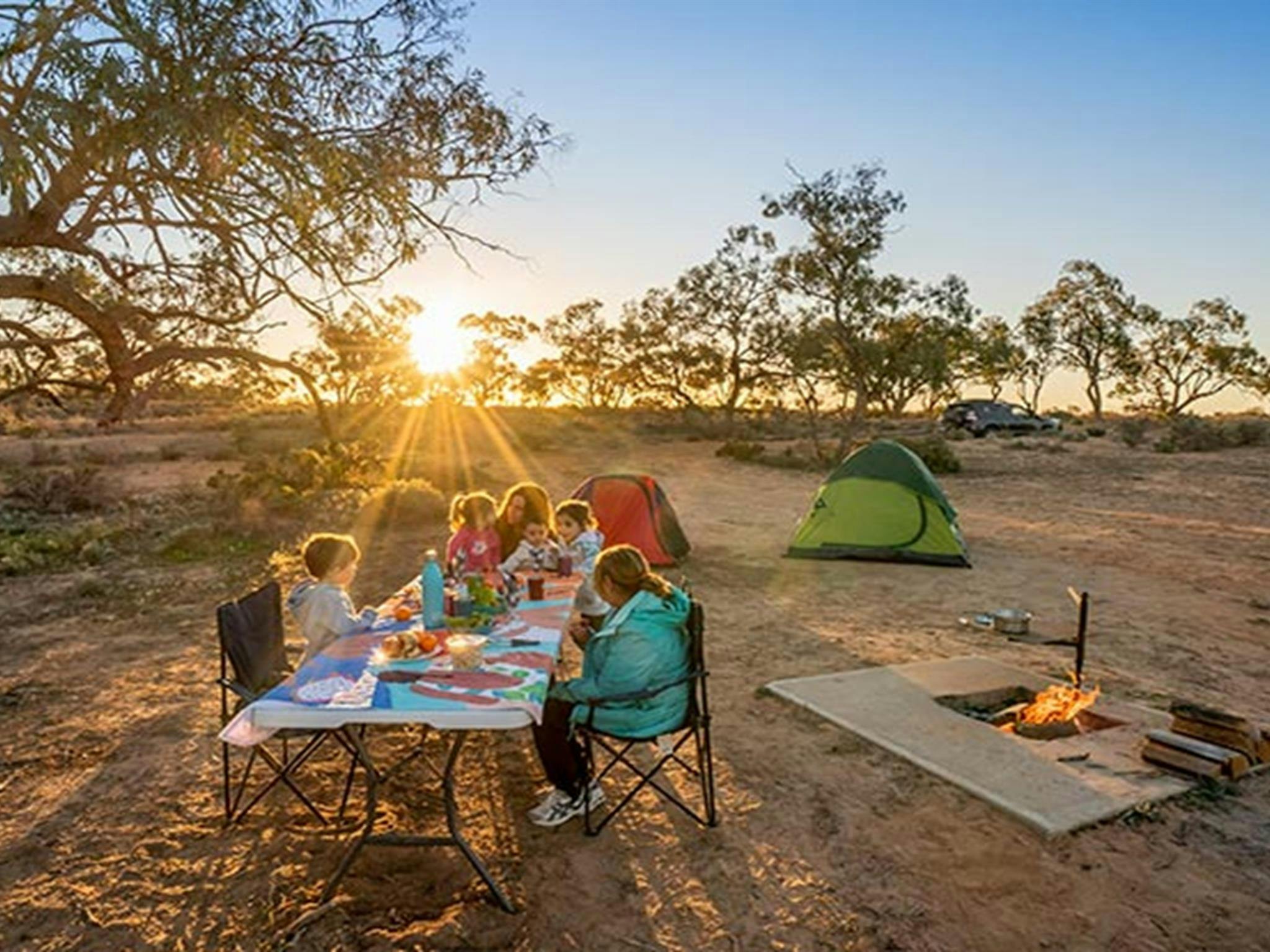Eine Familie genießt ein Abendessen bei Sonnenuntergang auf dem Campingplatz am Emu Lake. Foto: John Spencer/DPIE