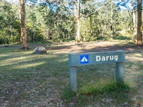 Signpost showing the Darug section of Euroka campground with toilets in the background. Photo: