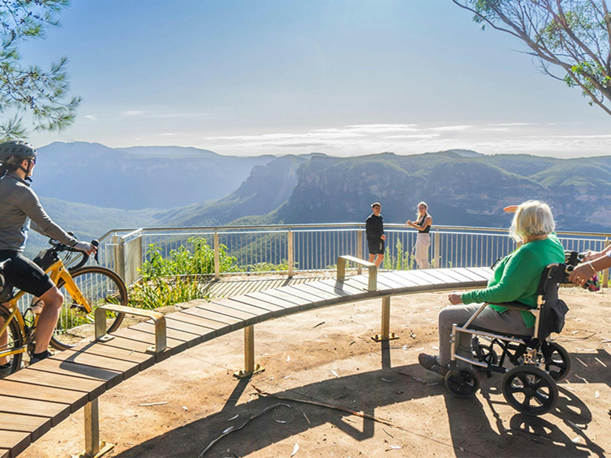 A cyclist on a bike, a person with reduced mobility in a wheelchair and other visitors at Evans