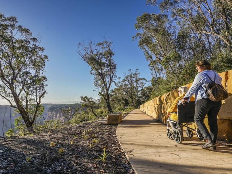 2 visitors along a path at Evans lookout in Blue Mountains National Park. Photo: Simone Cottrell/DPE