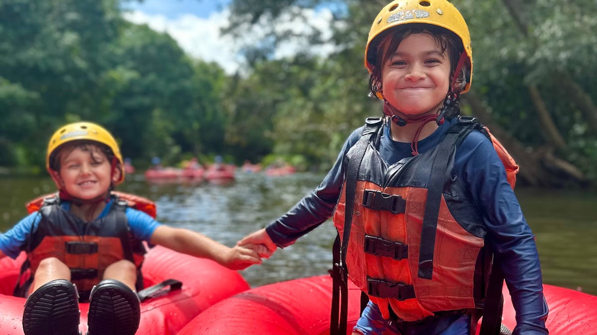 Young brothers hold hands as they tube through Wooroonooran National Park near Cairns