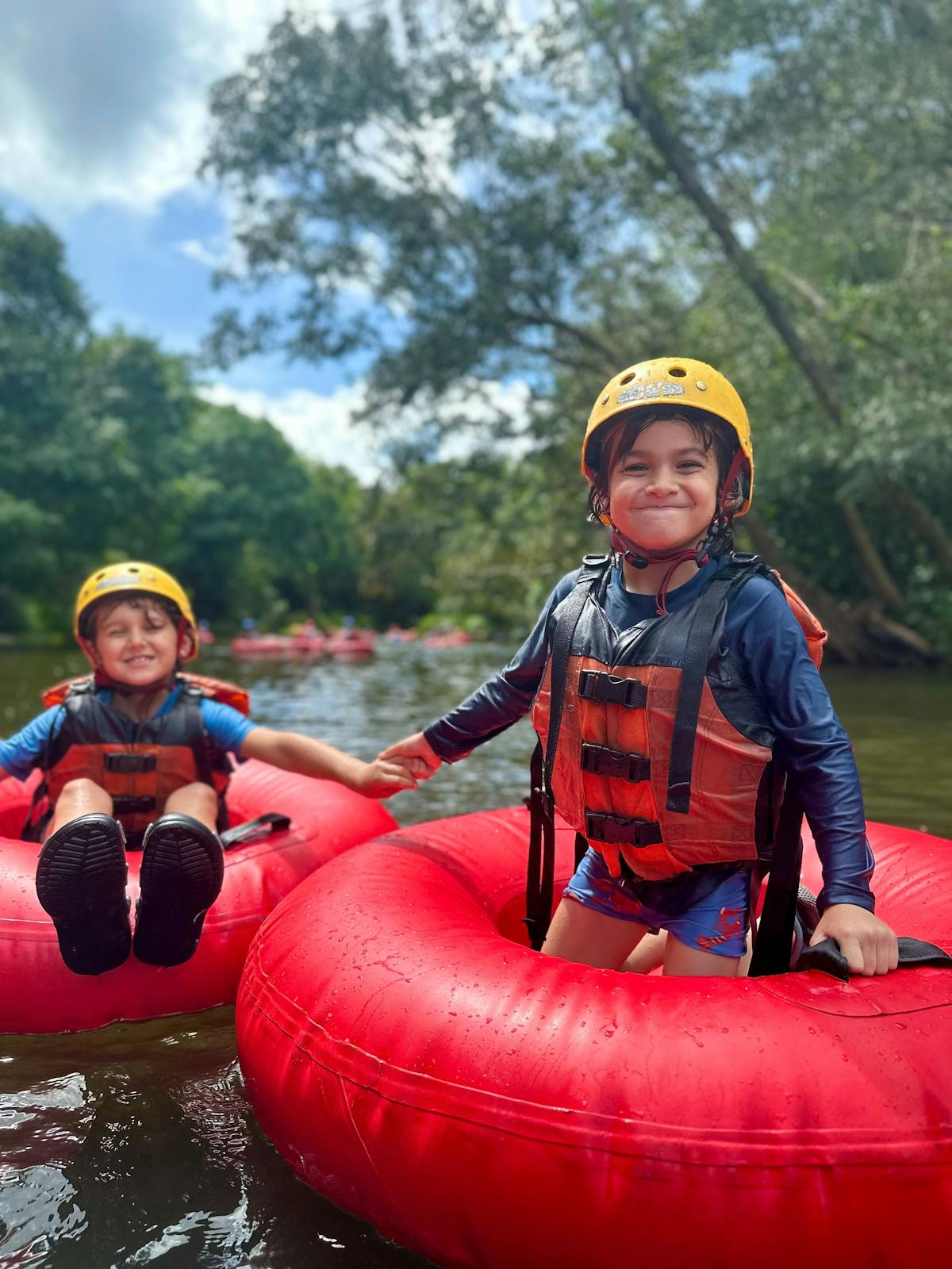 Young brothers hold hands as they tube through Wooroonooran National Park near Cairns