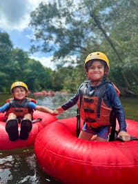Young brothers hold hands as they tube through Wooroonooran National Park near Cairns