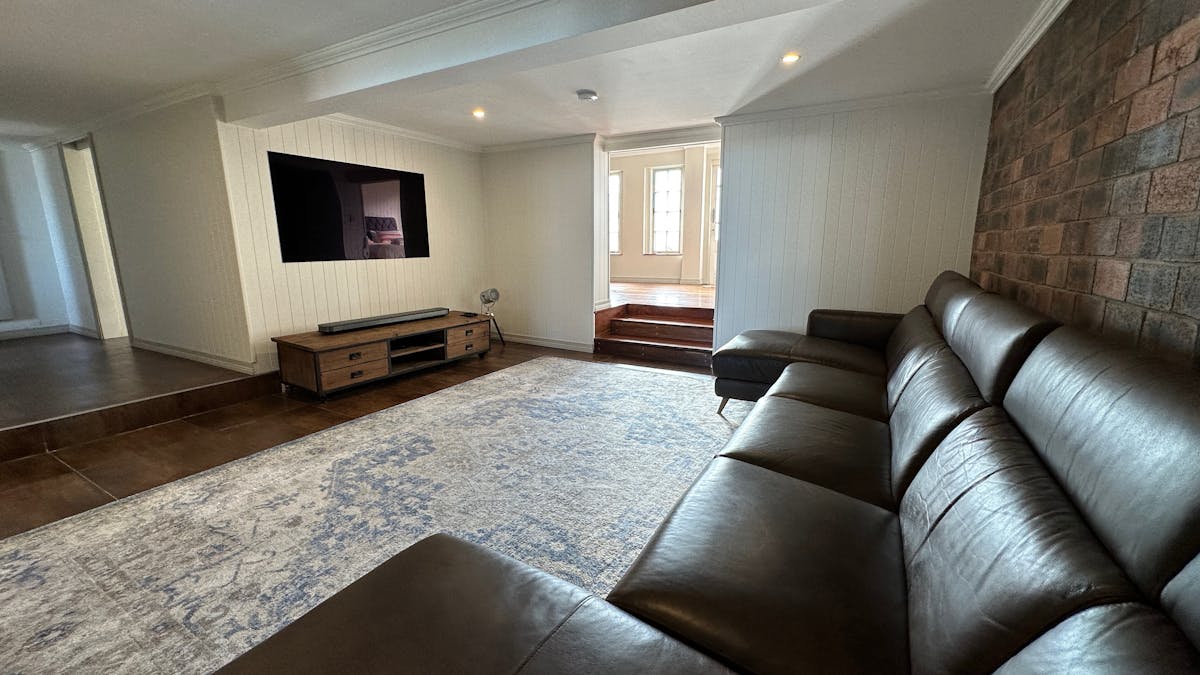 Large living area with leather reclining couch and wallpaper OLED tv