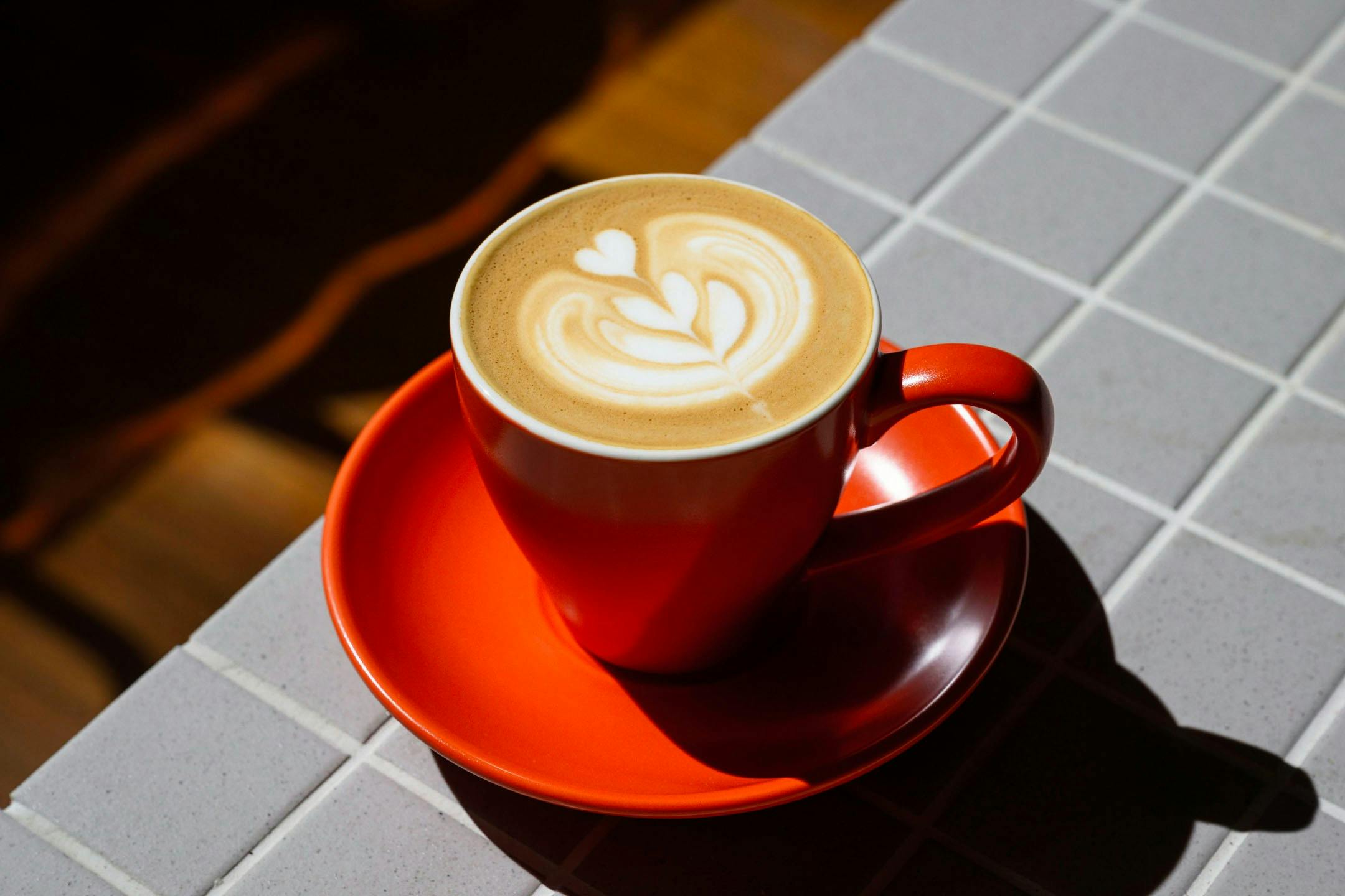 An orange coffee cup with latte art