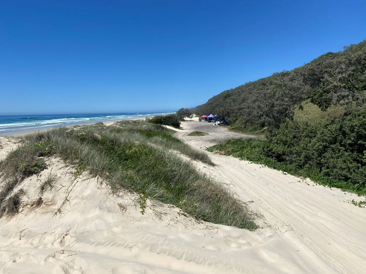 Coloured marquees set up behind the sand dunes.