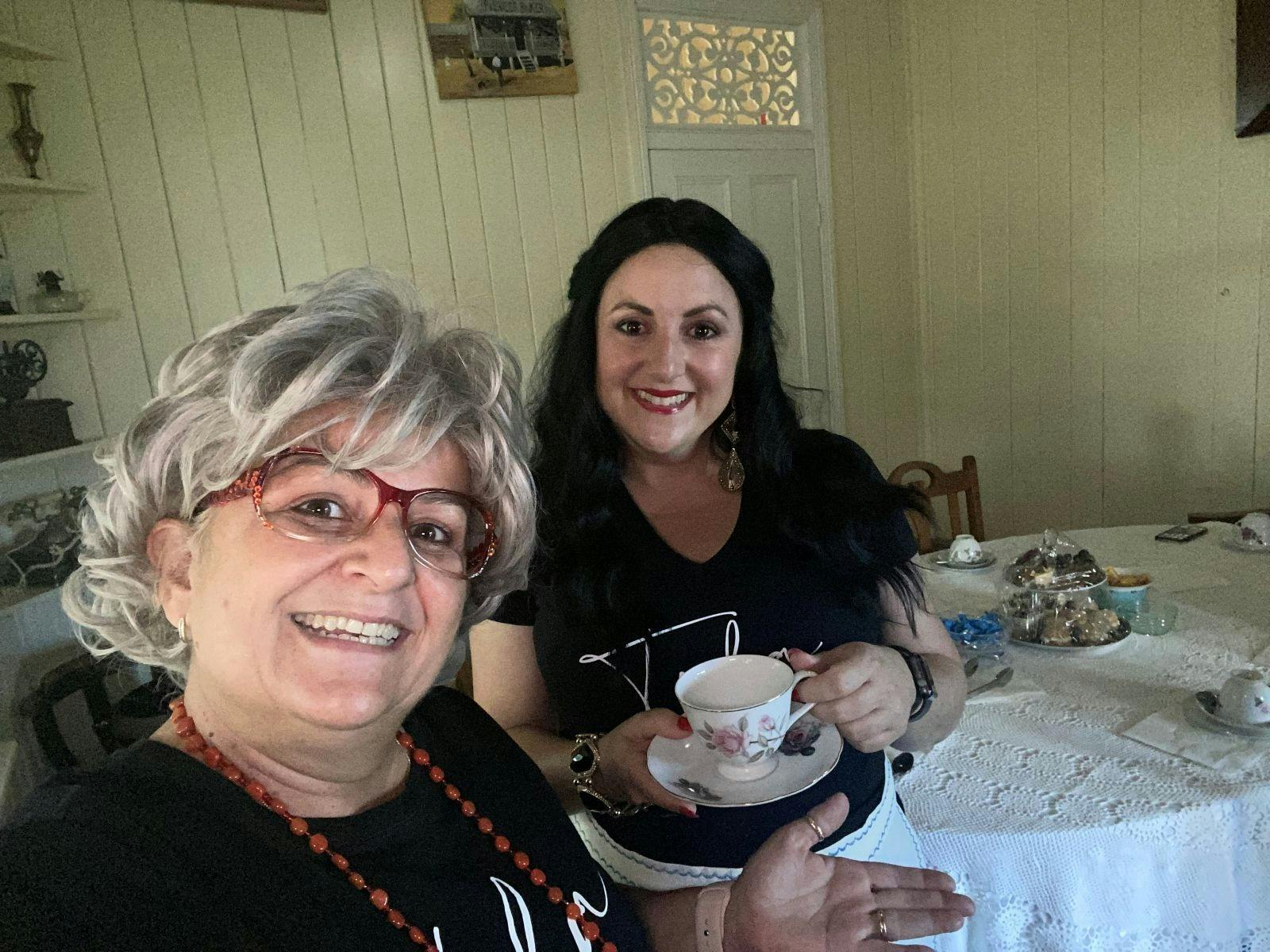 Comedy Tours Vula and Tula having a cup of tea with sweets