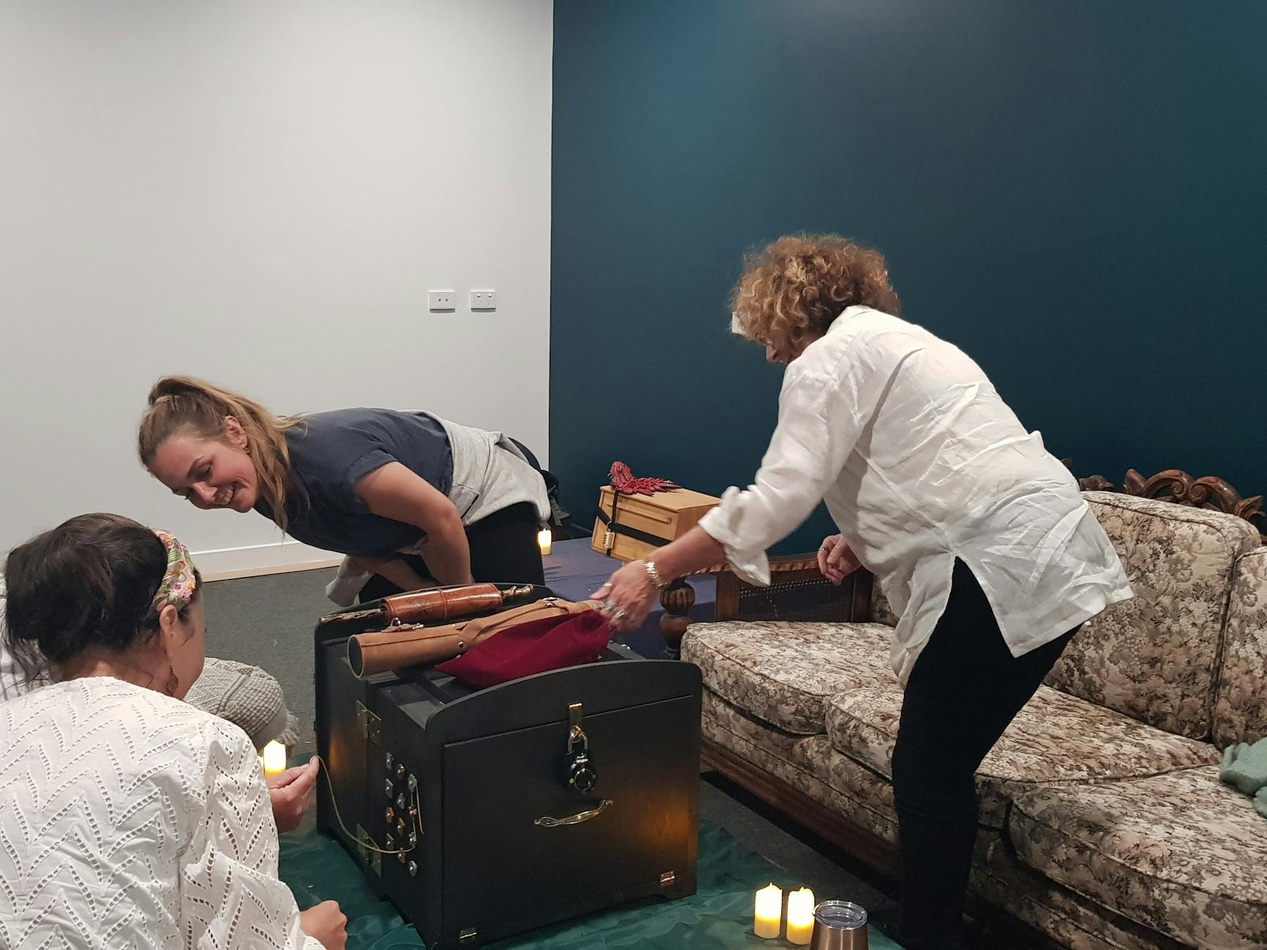 Four people solving puzzles to open a wizard-themed box with numerous buttons and locks.