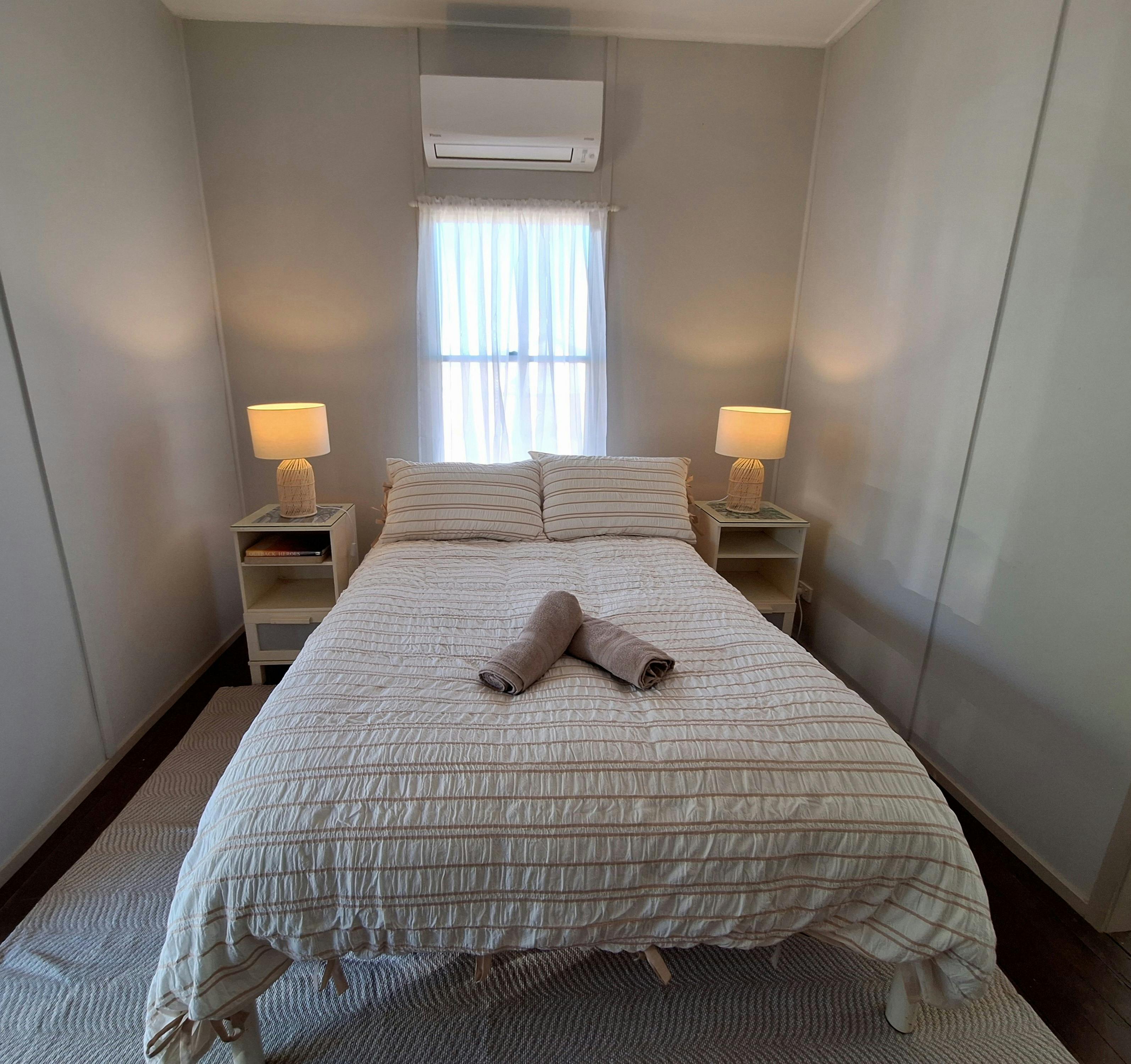 A double bed with towels placed at the foot of the bed and lamps either side of the bed