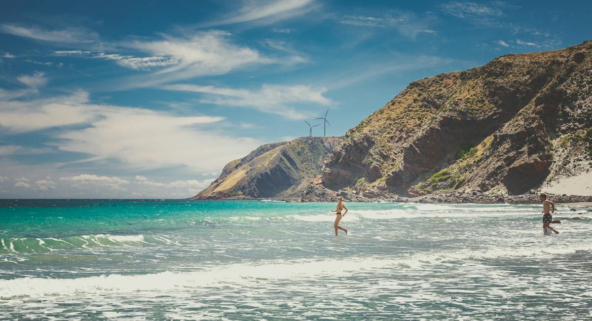 Two people running into the water at Morgans Beach