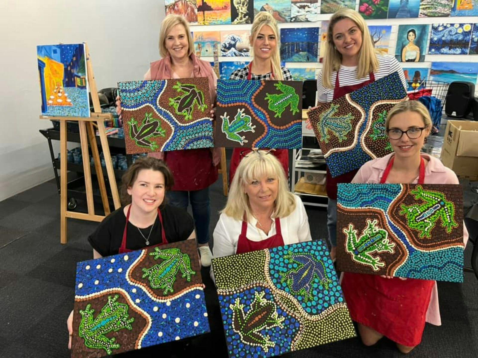 Group of women showing their paintings.