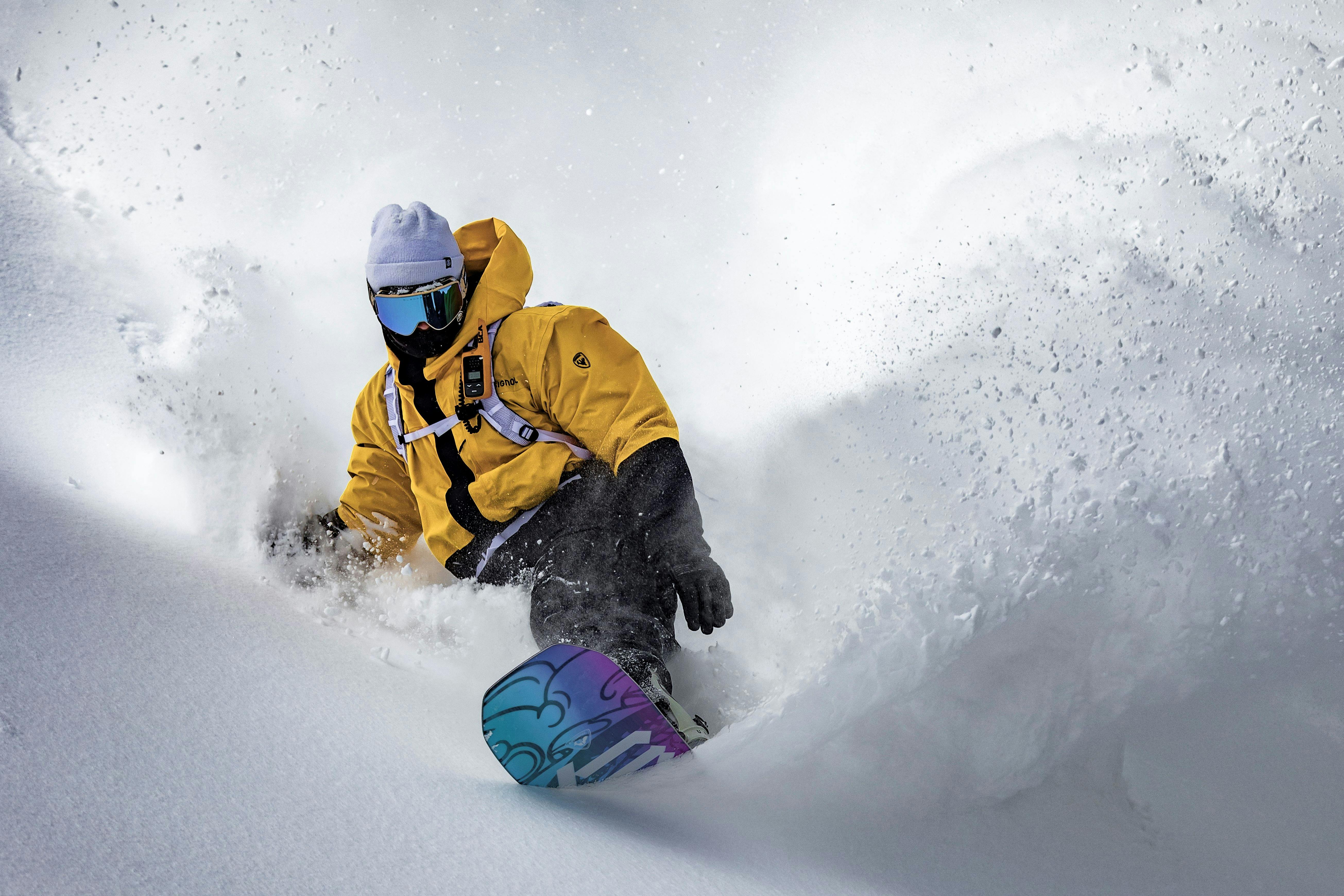Man in yellow jacket riding through powder snow