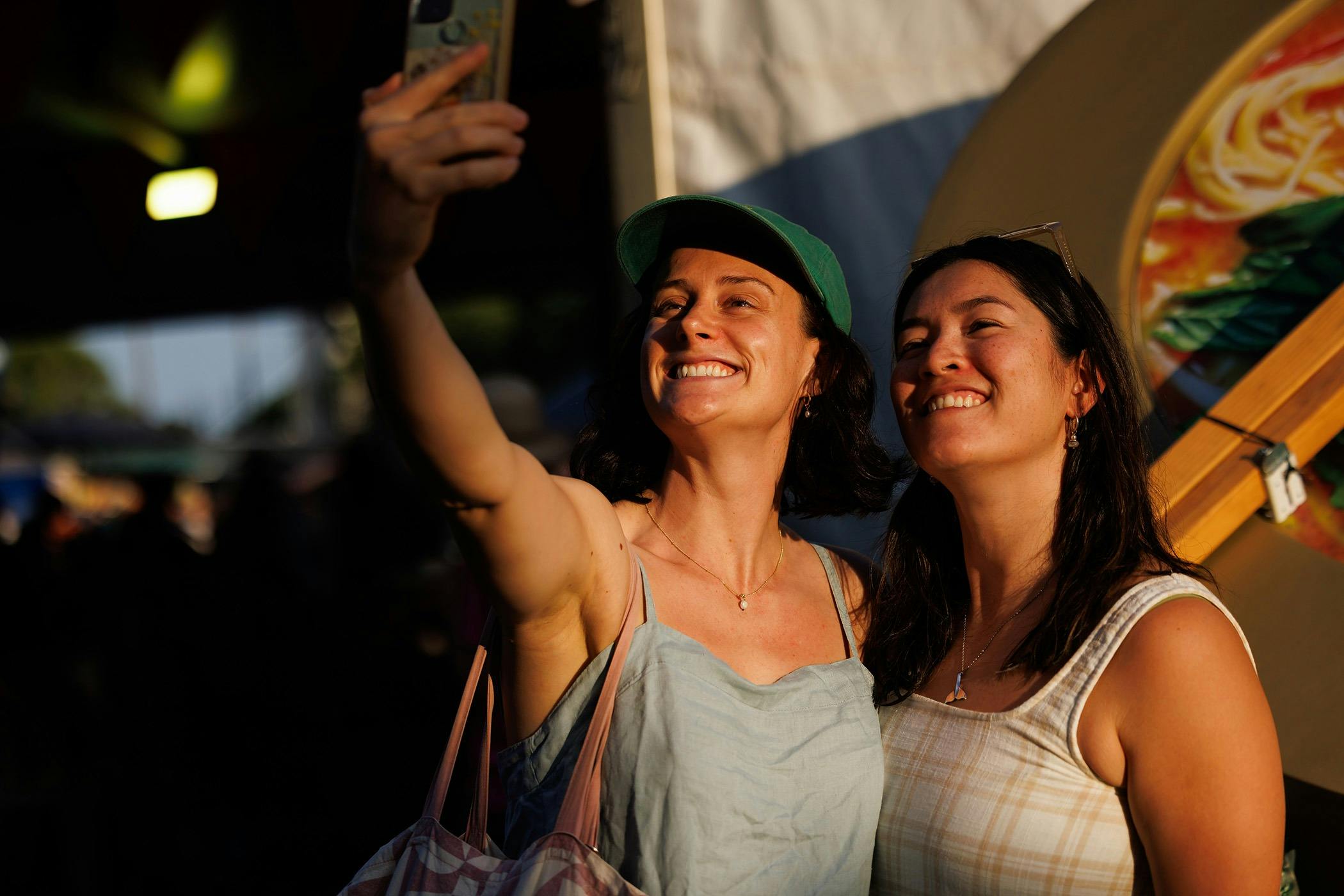 Two smiling festivalgoers taking a selfie in the afternoon sun at the Darwin Laksa Festival