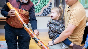 Indigenous Elder showing didgeridoo to tourists in the Greater Brisbane region