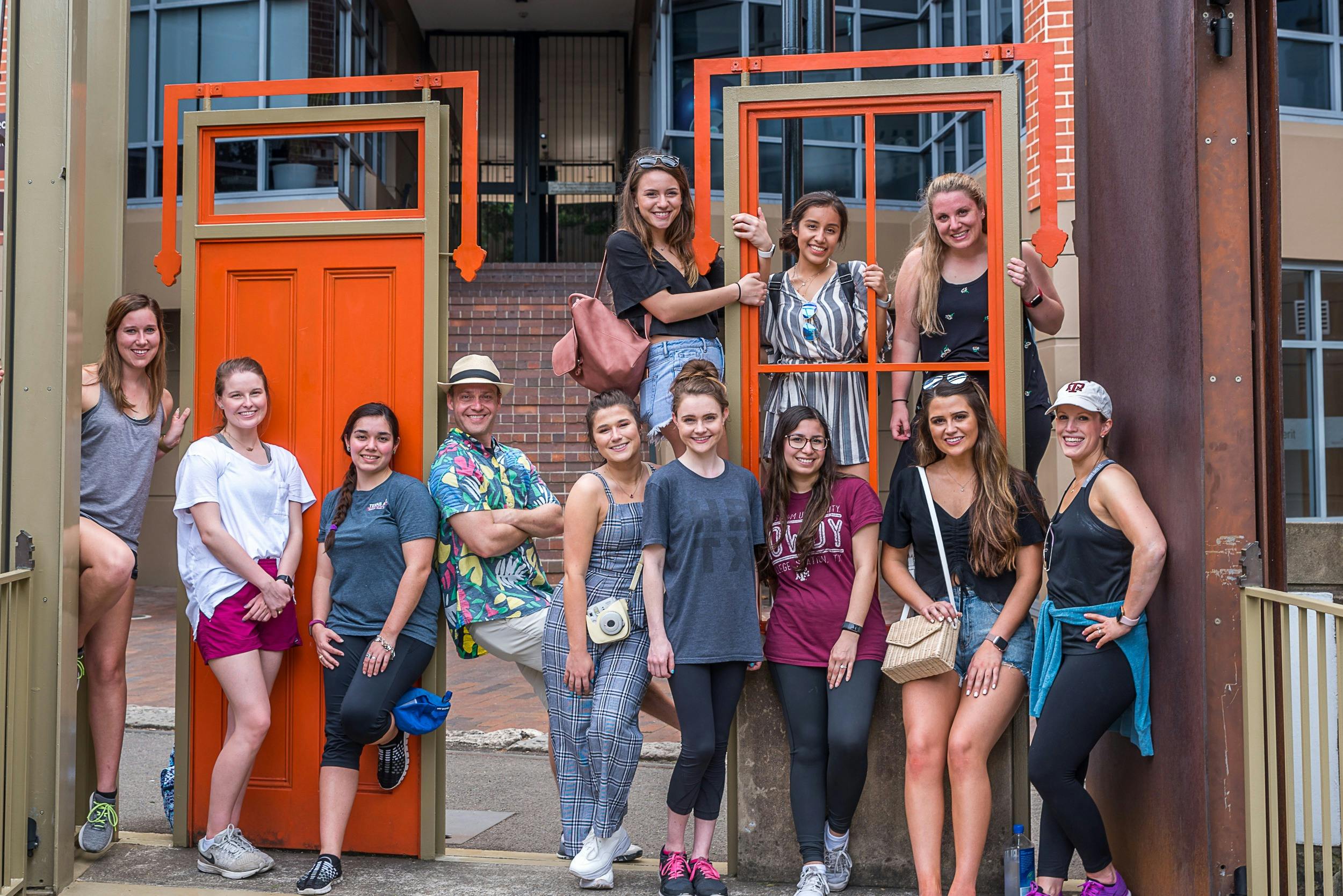 教師と若い女性のグループは、赤いドアのアートワークにさりげなく立っています