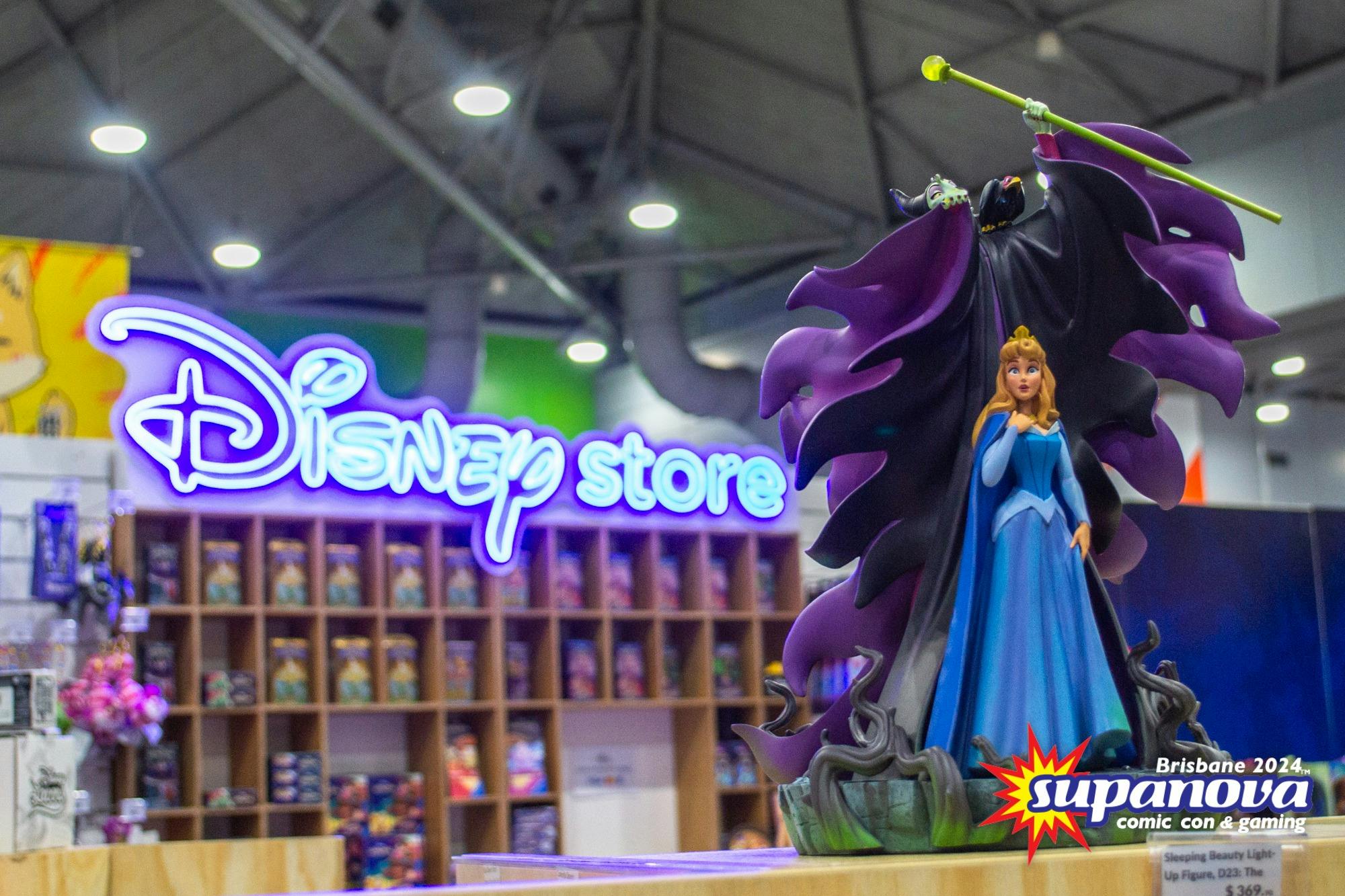 A Sleeping Beauty figurine featuring  is showcased in front of the glowing Disney sign