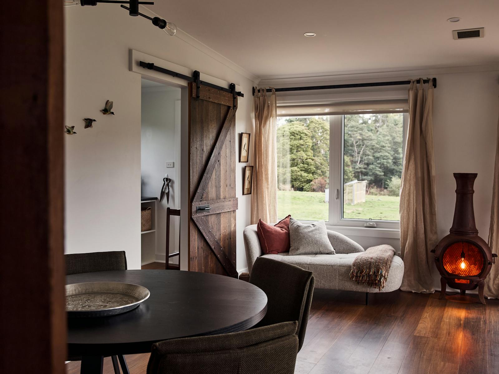 room with timber floor, round dining table and chairs, modern chaise
