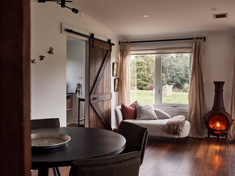 room with timber floor, round dining table and chairs, modern chaise