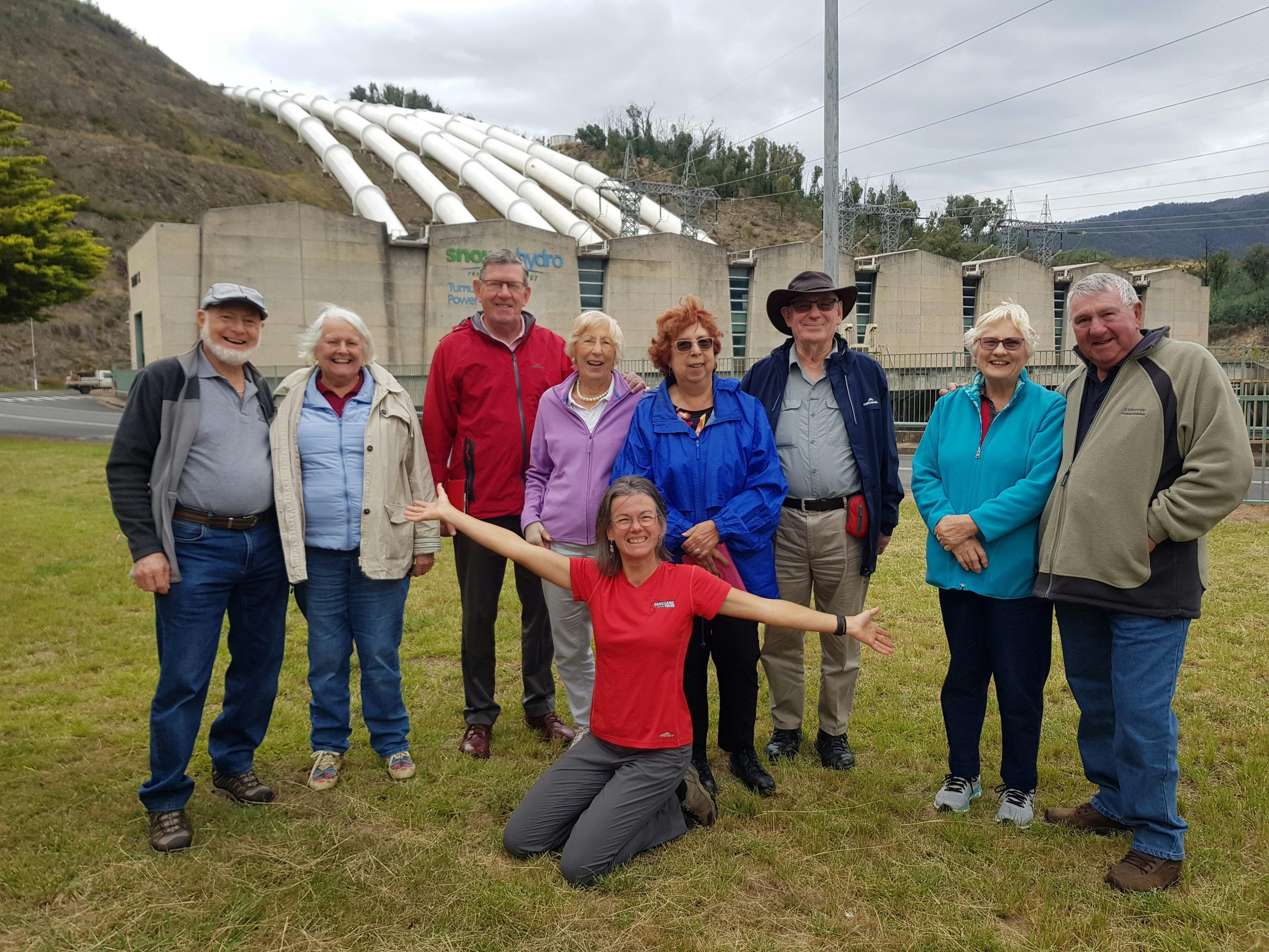 nine people in front of hydro electric power station