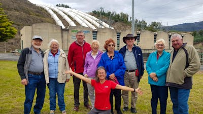nine people in front of hydro electric power station