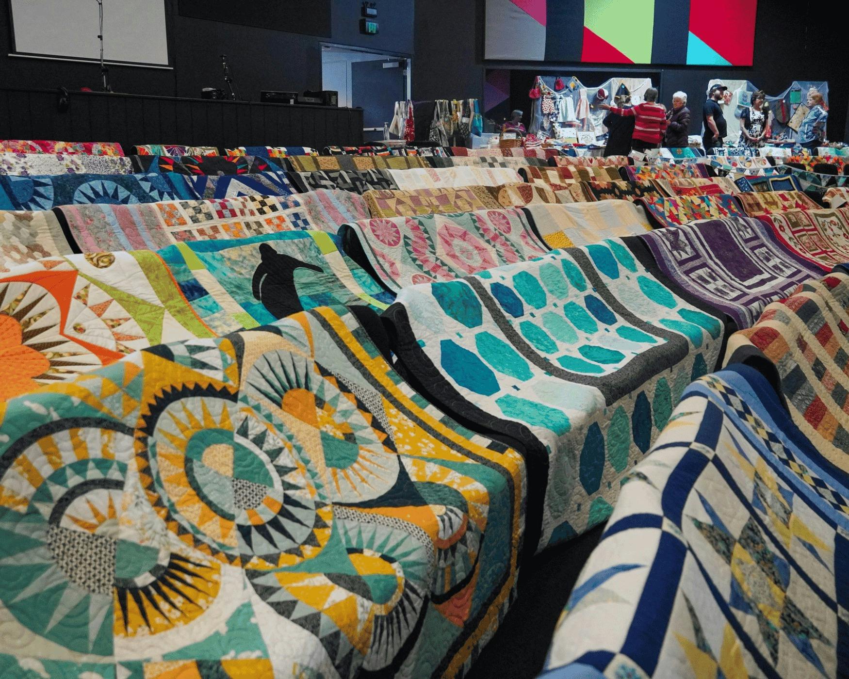 Many quilts displayed on chairs in Auditorium