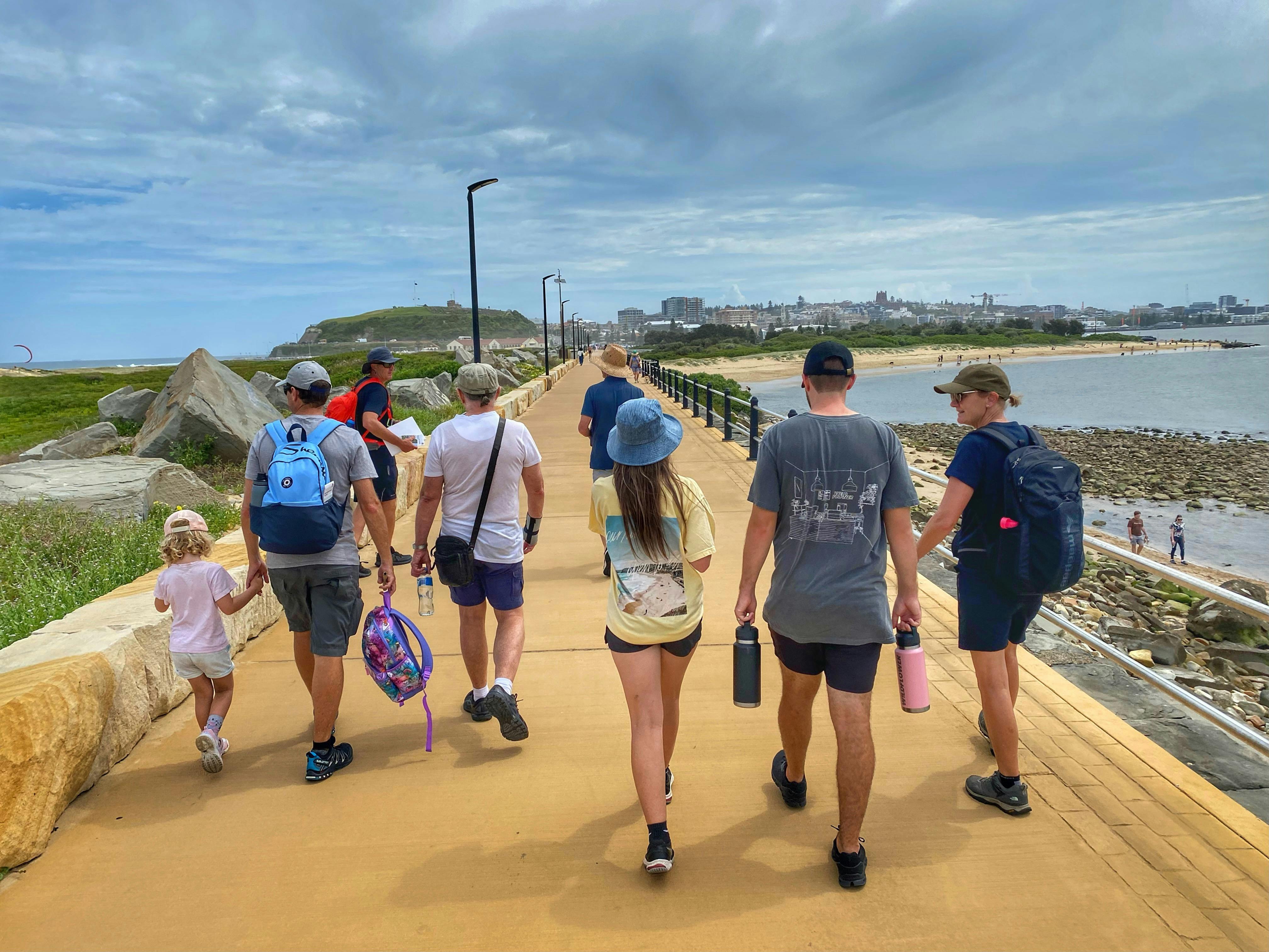 A group of people walking along a breakwater