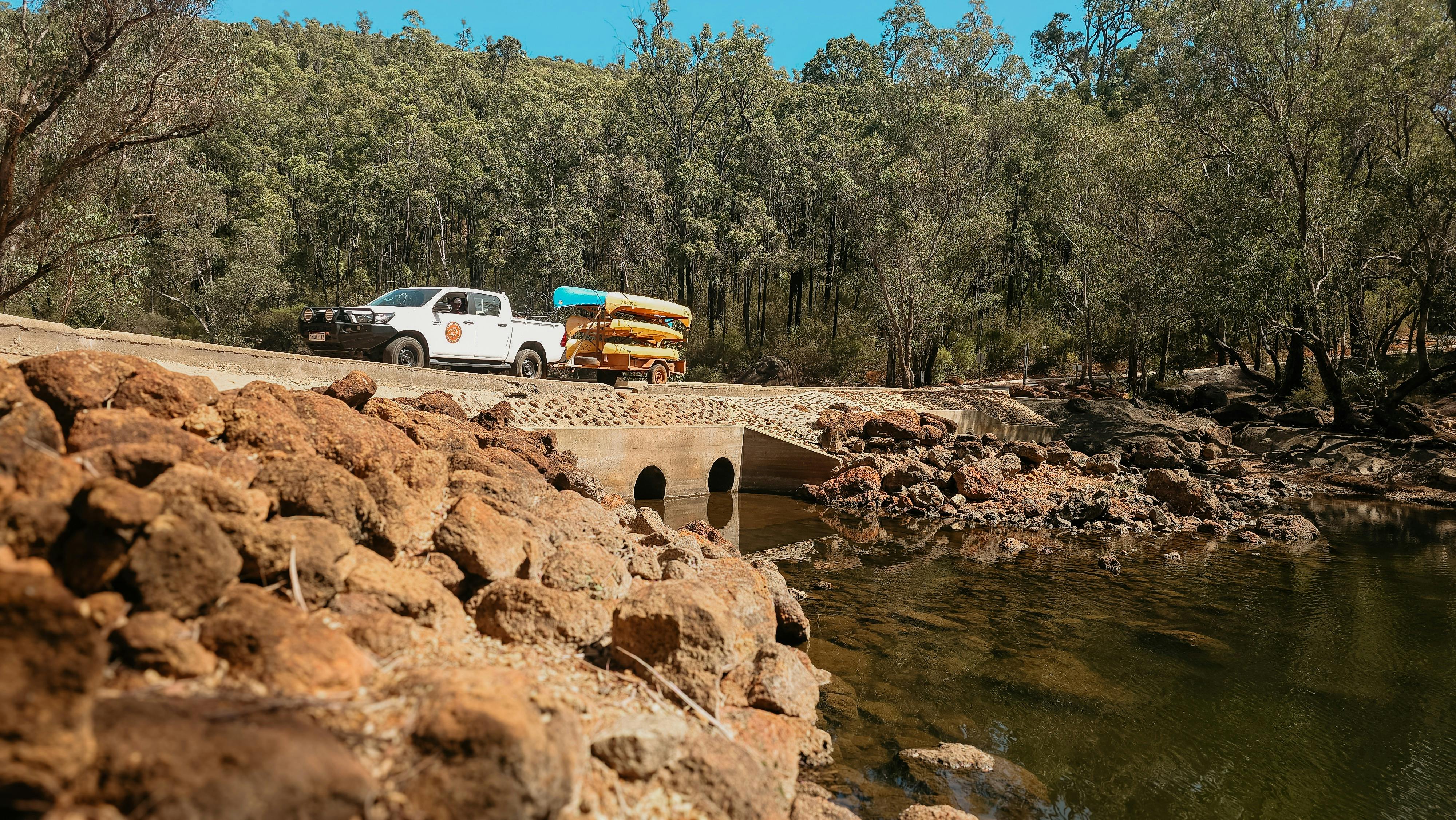 4WD crossing river towing canoes on trailer