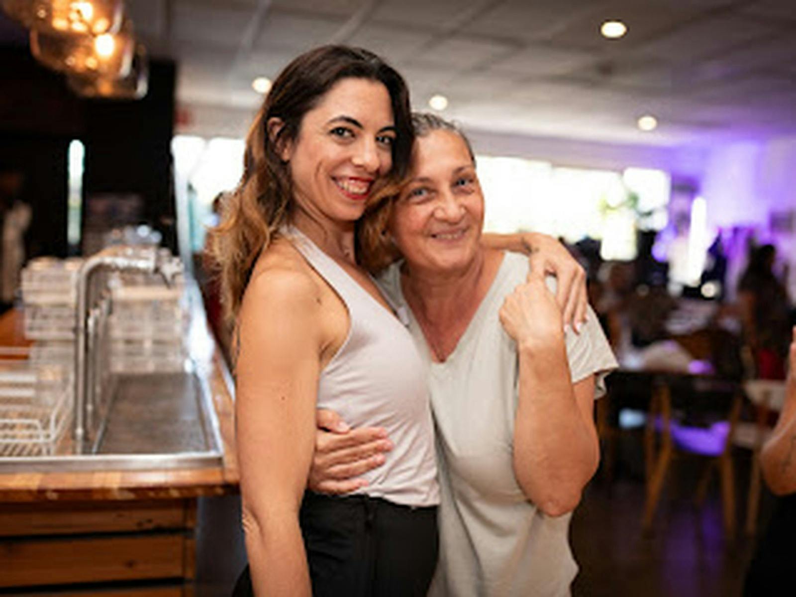 Two women smiling and embracing at a social dance event at QuickSteps Dance Club.