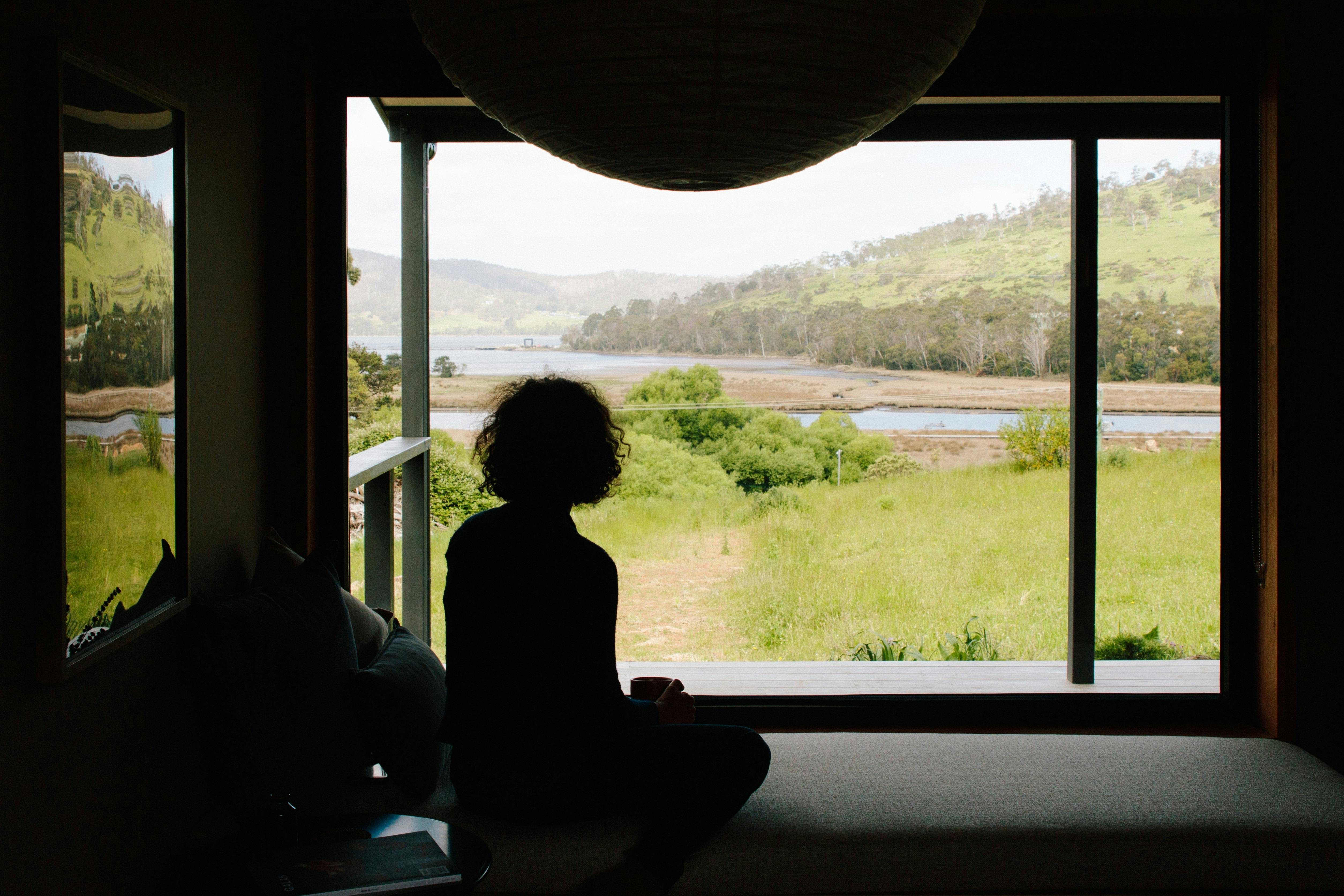 A person sits on the window seat looking out the window.
