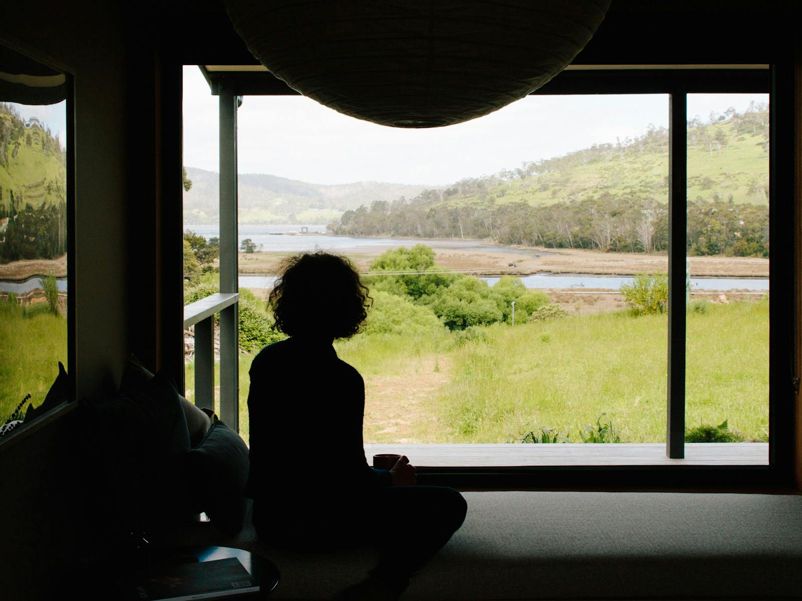 A person sits on the window seat looking out the window.