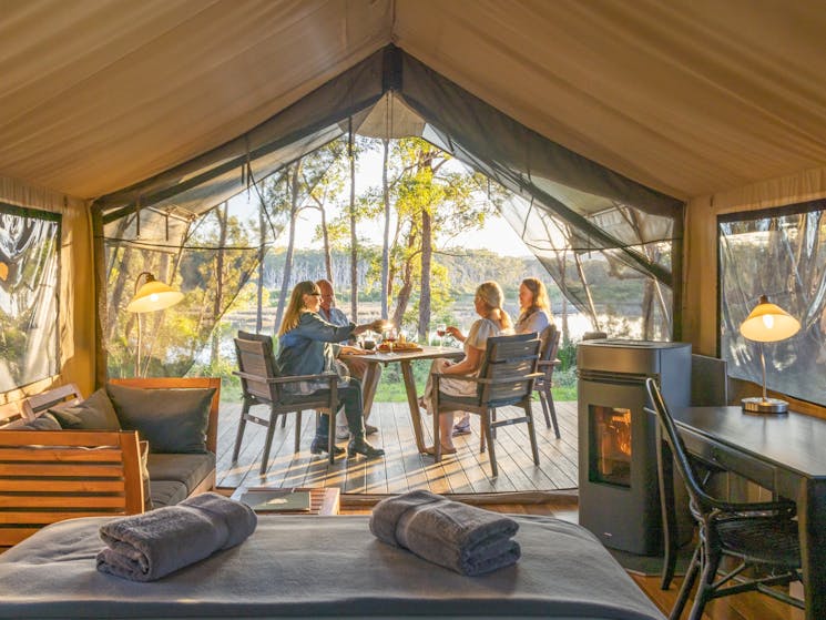Guests enjoying sunset drinks on deck of luxury safari tent