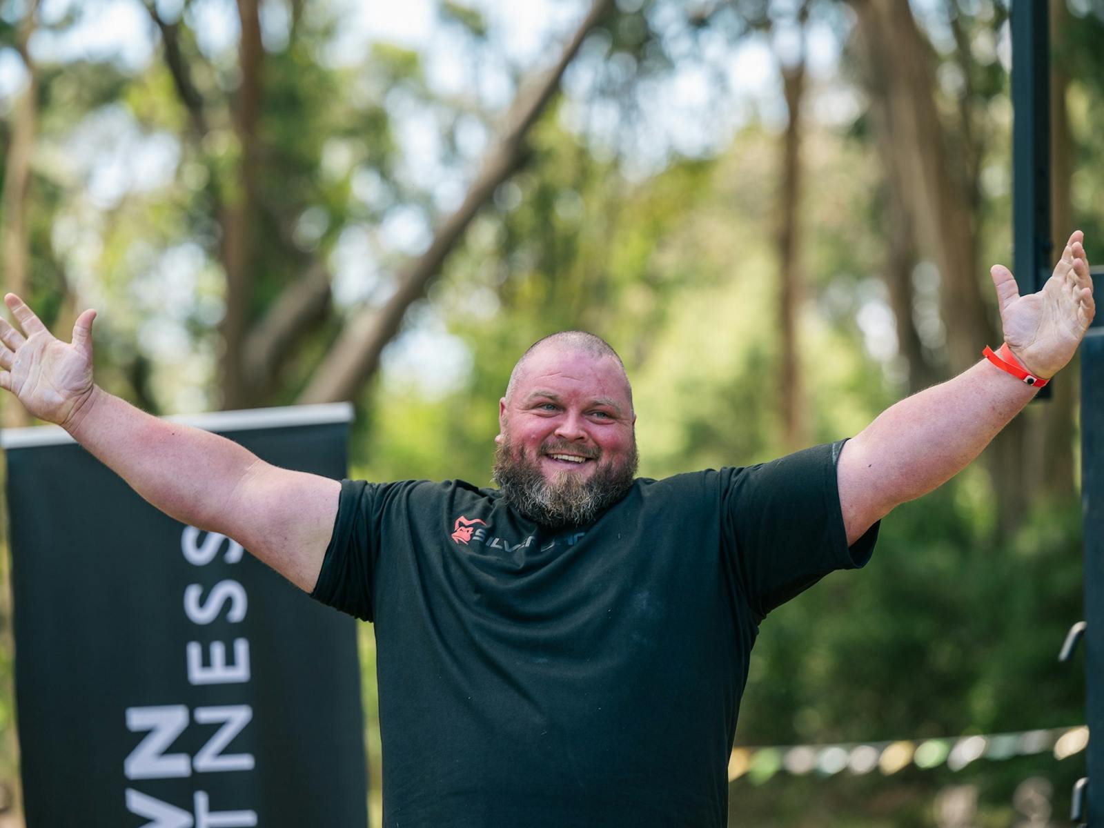 A strongperson competitor raising his hands after winning a competition