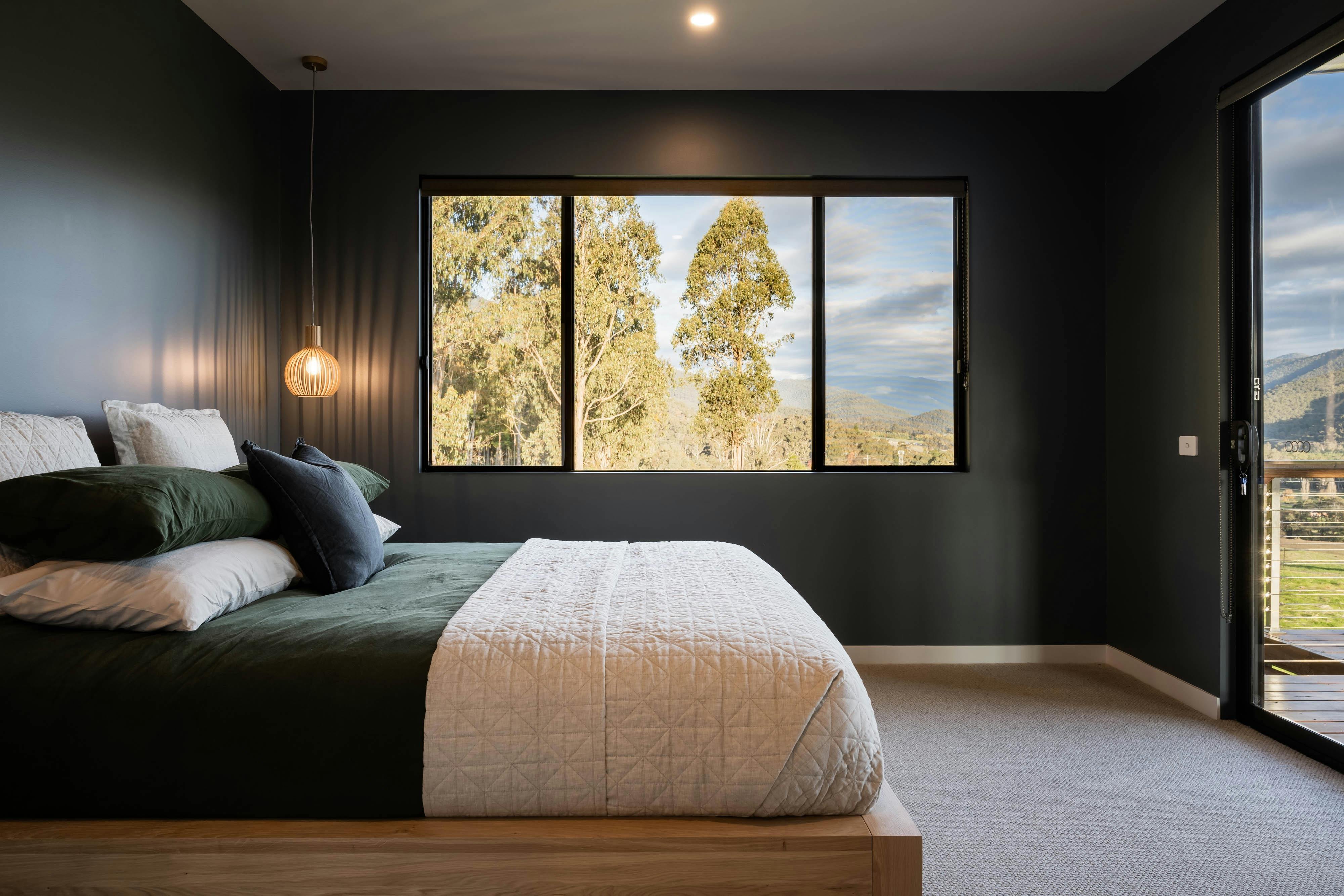 Large master bed with mountain views and door opening onto veranda