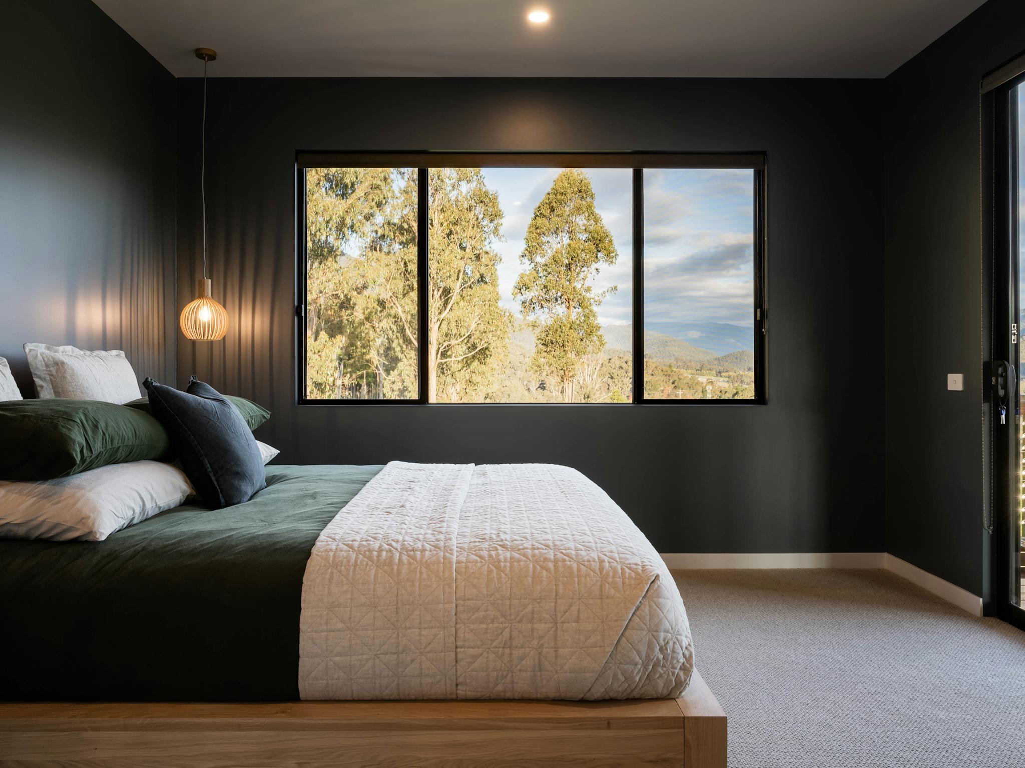 Large master bed with mountain views and door opening onto veranda