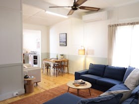Open-plan kitchen and living area with a dining table in the centre and a modular sofa beyond.